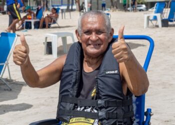 Cadeira anfíbia auxiliar pessoa idosa a tomar banho de mar assistida